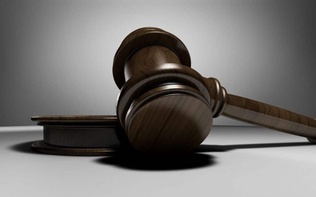 Una maza de madera de juez descansando en su soporte contra un fondo gris, simbolizando la nueva ley de igualdad de trato y no discriminación.